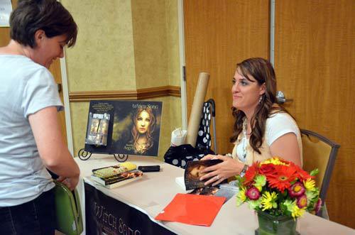 Author Amber Argyle (Smith) signing books for a guest at the Rhemalda Publishing Got Stories Conference in Salt Lake City, Utah.