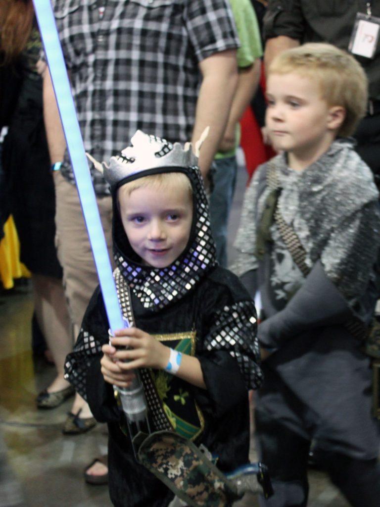 DEH wielding a star wars lightsaber while in a medieval knight costume.