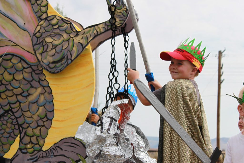 A child fighting a dragon on a parade float.