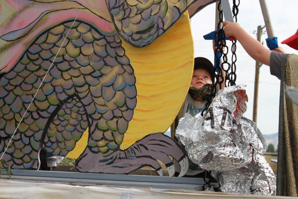 A child fighting a dragon on a parade float.