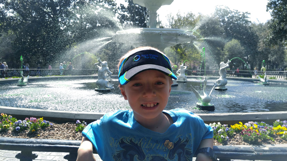 A young boy standing in front of the fountain at Forsyth Park.