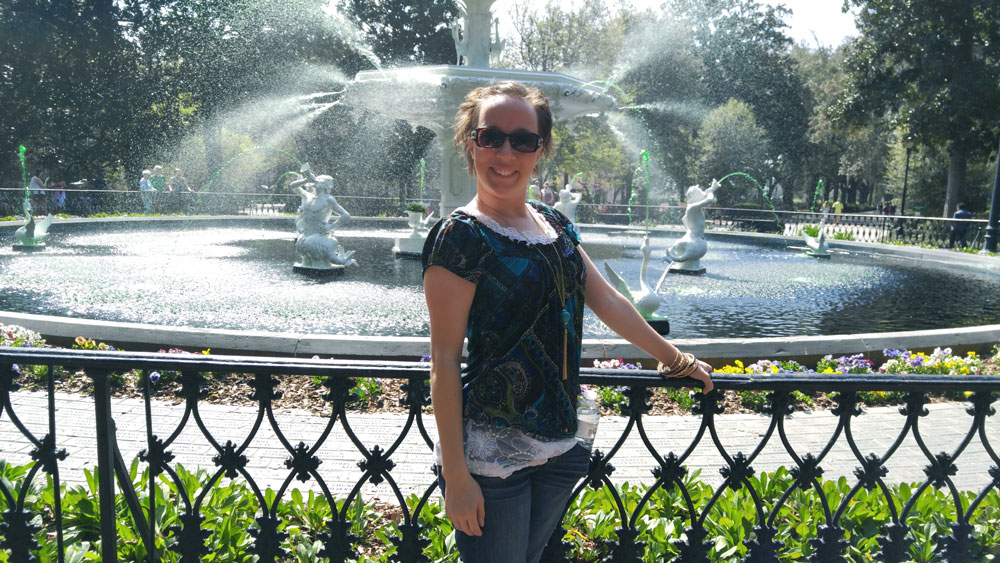 A woman standing in front of the Forsyth Park fountain in Savannah Georgia.