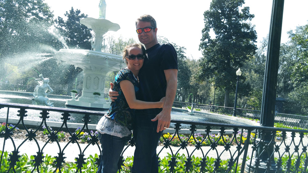 A couple standing in front of the fountain at Forsyth Park in Savannah, Georgia.